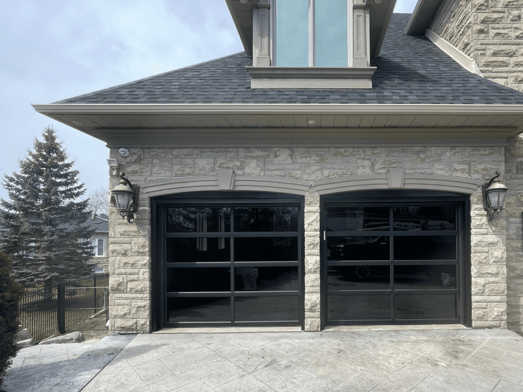 Installation of a sleek black aluminum garage door featuring double tinted windows, by Penguin Garage Doors Newmarket.