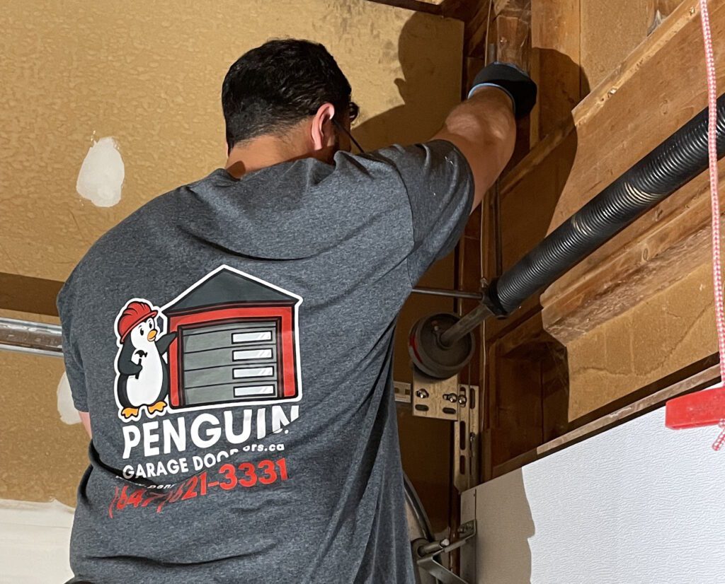 Penguin Garage Doors Technician adding tension to a replacement torsion spring during broken garage door spring replacement in Thornhill.